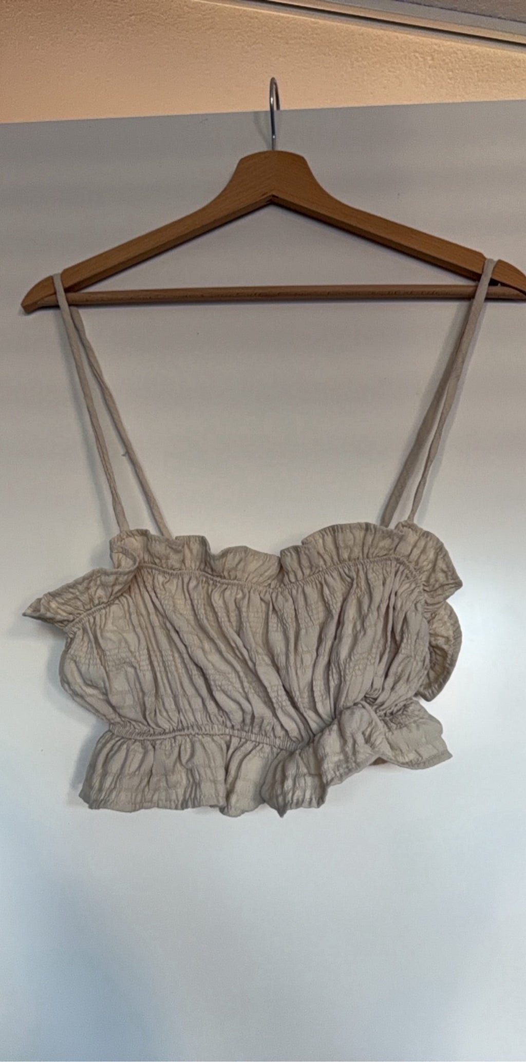 Mai Collection beige crop top with ruffle details and adjustable lace-up back.