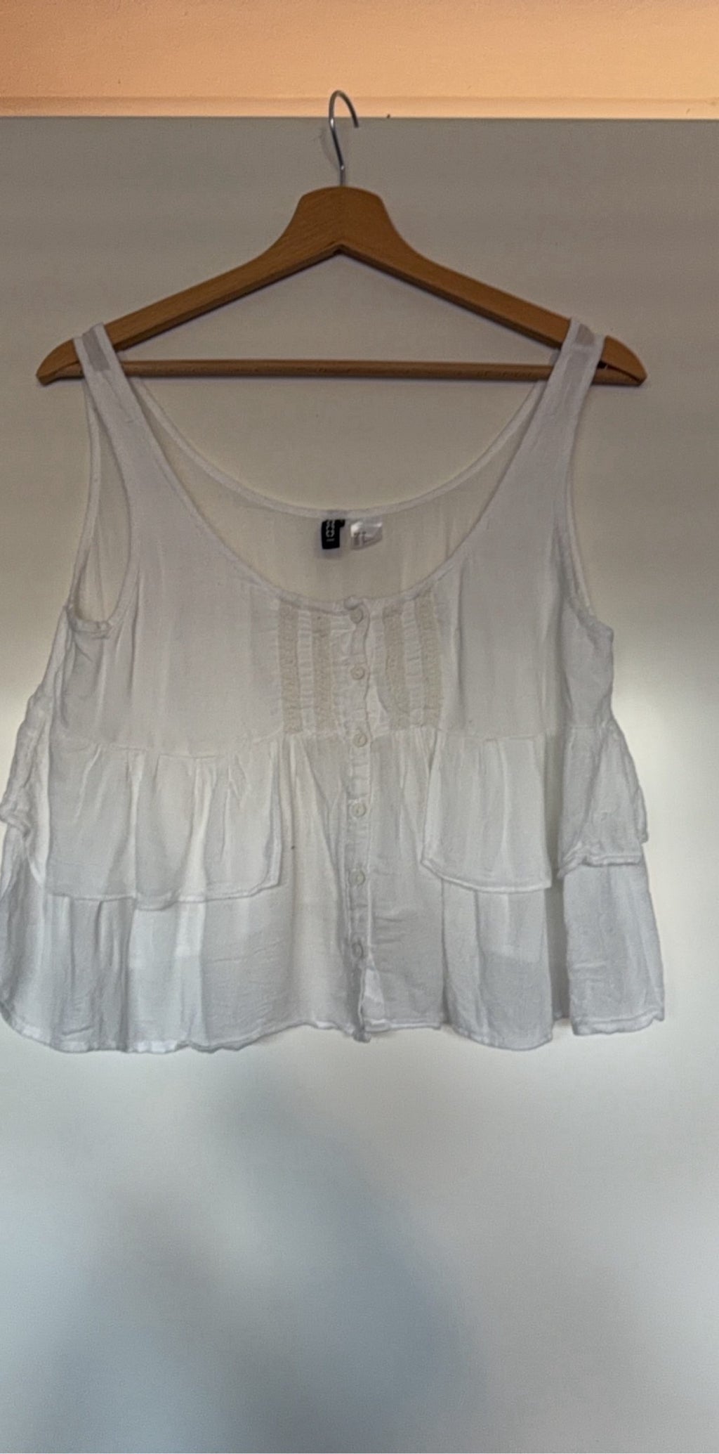 H&M white crop top with ruffled tiers and decorative button-up front.