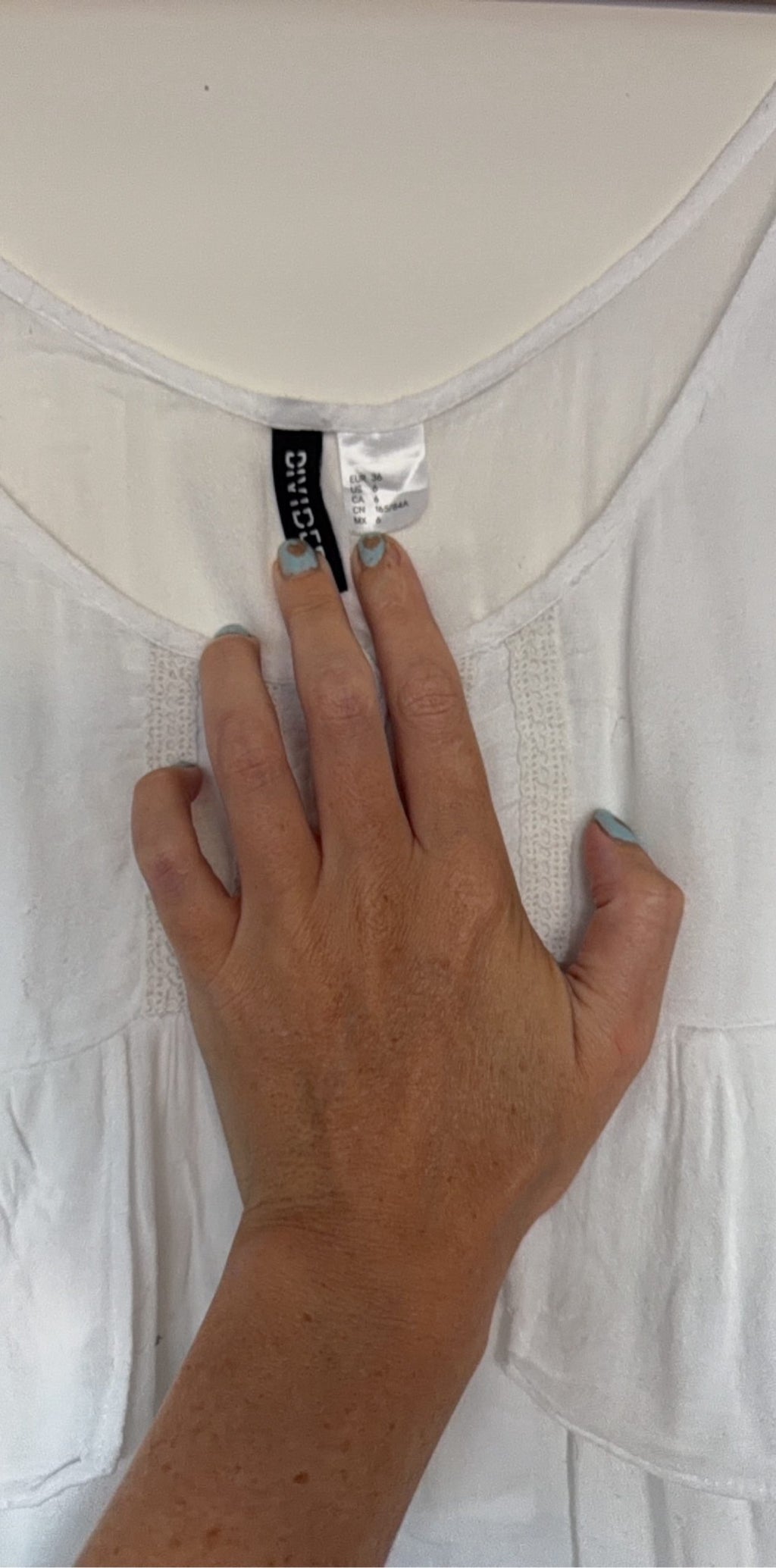 H&M white crop top with ruffled tiers and decorative button-up front.