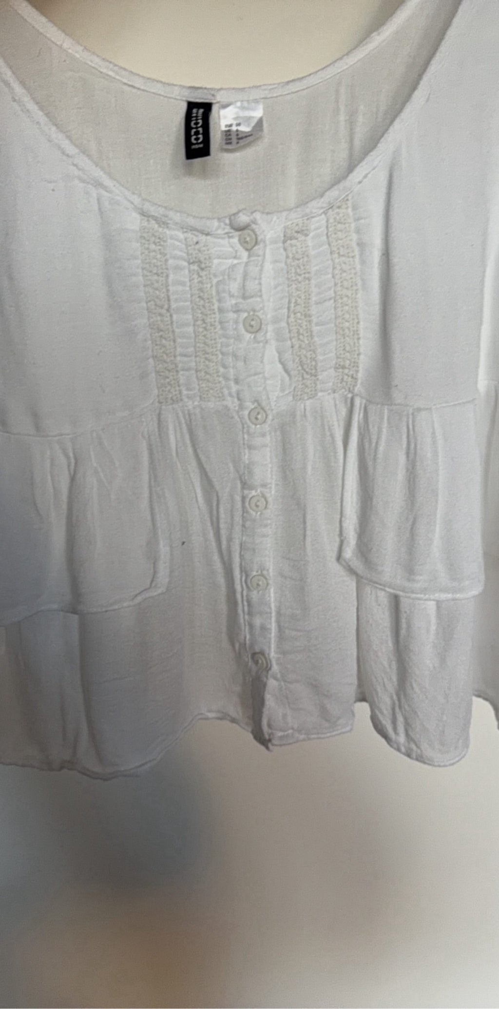 H&M white crop top with ruffled tiers and decorative button-up front.