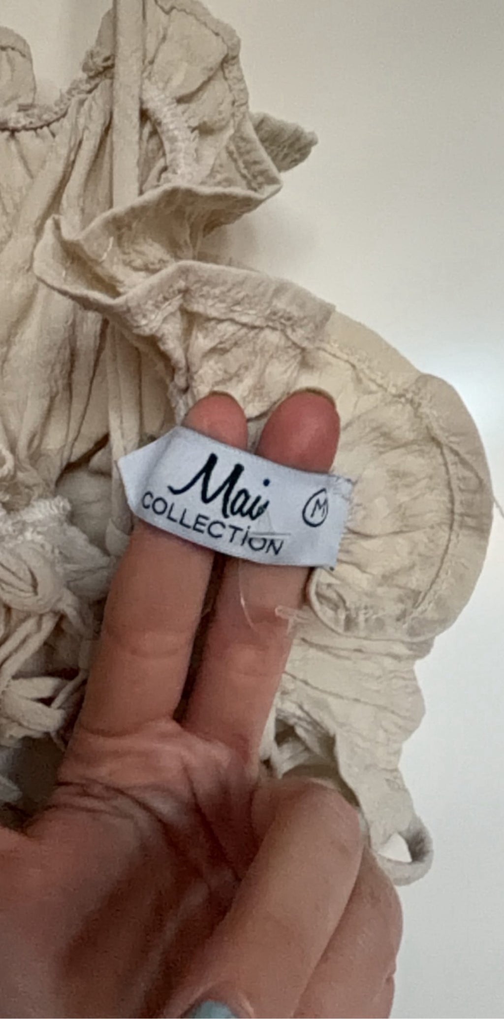 Mai Collection beige crop top with ruffle details and adjustable lace-up back.