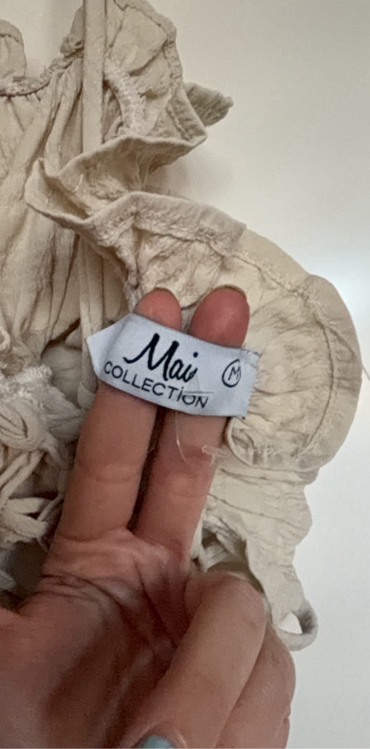 Mai Collection beige crop top with ruffle details and adjustable lace-up back.